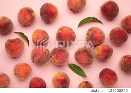 Ripe red peaches with green leaf on pink background. 128208246