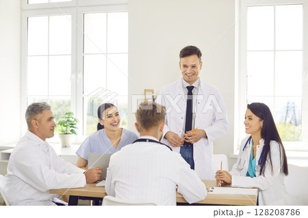Group of happy doctors in a clinic sitting together at a table, close-up Group of happy doctors in a clinic sitting together at a table, close-up 128208786