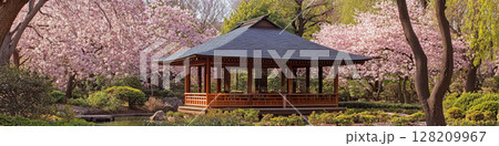 A traditional wooden pavilion with a pointed roof sits among blooming cherry trees and lush greenery. Concept of tranquility and natural beauty. For garden design ideas. A traditional wooden pavilion with a pointed roof sits among blooming cherry trees and lush greenery. Concept of tranquility and natural beauty. For garden design ideas. 128209967