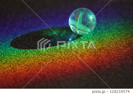 Small, clear, round ball sits on a dark surface 128210574