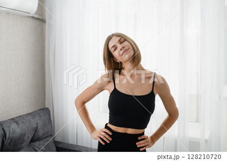 Smiling young woman tilting head during morning exercise. 128210720