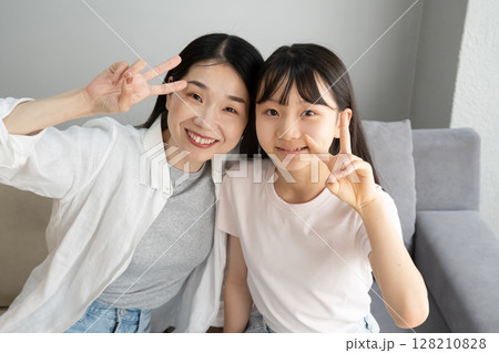 屋内でピースサインをする母娘 屋内でピースサインをする母娘 128210828