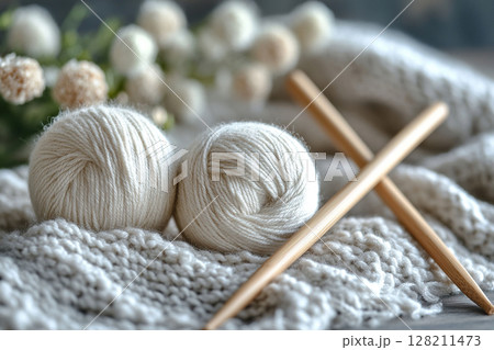 Ball of white thread and knitting needles lie on light yarn. Concept of knitting and home comfort. Generated by artificial intelligence 128211473