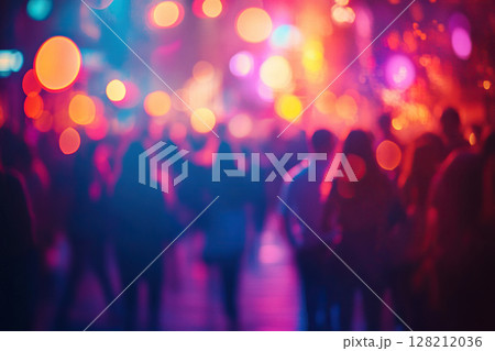 A blurry image of a busy city street at night, illuminated by bright neon lights. A crowd of young people on the street creates a party atmosphere 128212036