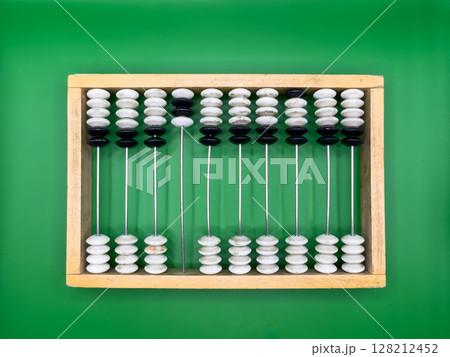 Russian old wooden abacus made of black and white pebbles and beige frame on dark green background in the center top view Russian old wooden abacus made of black and white pebbles and beige frame on dark green background in the center top view 128212452