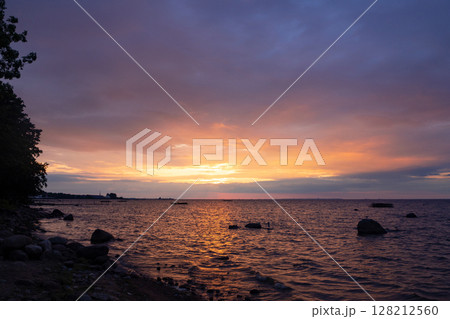 Scenic sunset on the beach in pink shades. The waves are rolling on the shore. Cloudy summer evening. Scenic sunset on the beach in pink shades. The waves are rolling on the shore. Cloudy summer evening. 128212560
