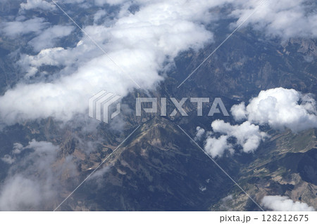 Aerial View of Mountain Peaks Partially Covered By Puffy Clouds 128212675