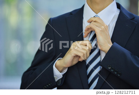 ビジネス街でネクタイを締める若い男性 128212711