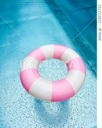 Swimming ring with pink and white stripes in a blue outdoor pool. Poolside atmosphere. Pink float. 128212722