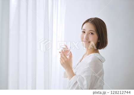 リビングで水を飲む若い女性 128212744