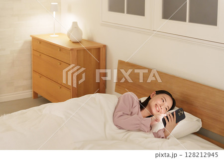 夜ベッドでスマホを使う女性 128212945