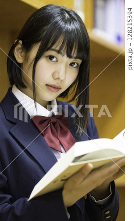 本を手にカメラを見つめる女子高校生｜図書館での落ち着いた学習シーン 128215394