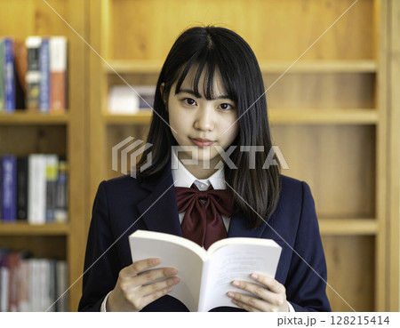 本を手に静かにカメラを見つめる女子高校生｜図書館での学びのワンシーン 128215414