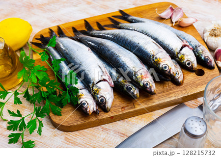 Fresh sardine, lemon and garlic on a kitchen board 128215732