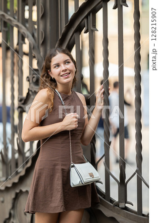 Young woman standing near the metal fence Young woman standing near the metal fence 128215907