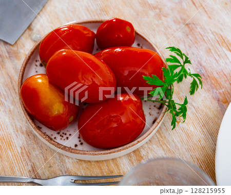 Homemade savory pickled tomatoes served on plate with fresh greens Homemade savory pickled tomatoes served on plate with fresh greens 128215955
