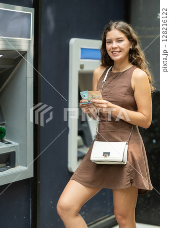 Young woman standing near ATM 128216122