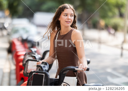 young woman stands in front of a cart of bicycles in the city 128216205