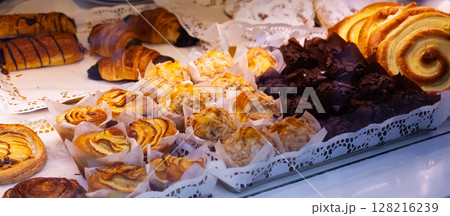 Closeup of sweet pastries behind glass on bakery showcase Closeup of sweet pastries behind glass on bakery showcase 128216239