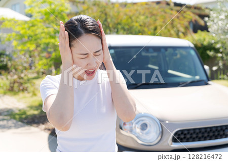 車の横で頭を抱える女性 128216472