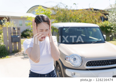 車の横で頭を抱える女性 128216474