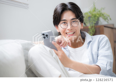 スマホを見る、持つ眼鏡のハンサムな男性のクローズアップ　カメラ目線 128216571