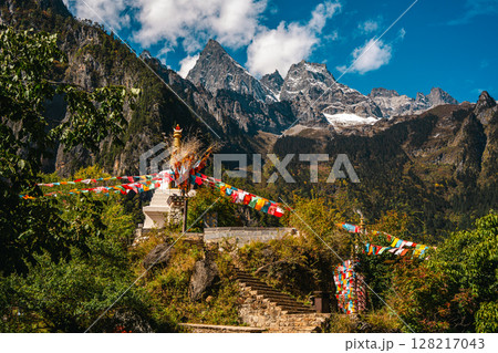 Tibetan Stupa with Prayer Flags and Snowy Peaks in Balagezong, Shangri-La, Yunnan. 128217043