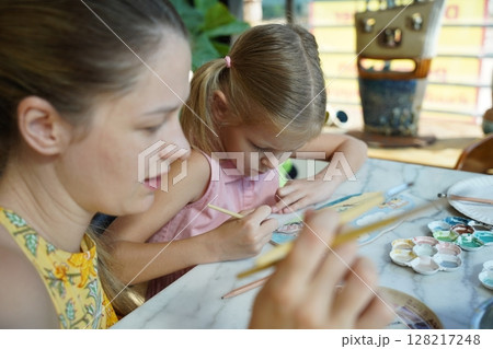 A young mother and her daughter enjoy a creative art session at home  128217248