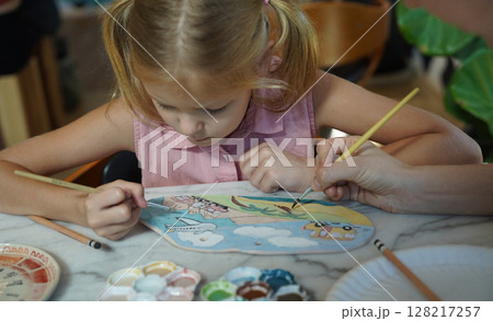 A young mother and her daughter enjoy a creative art session at home  128217257