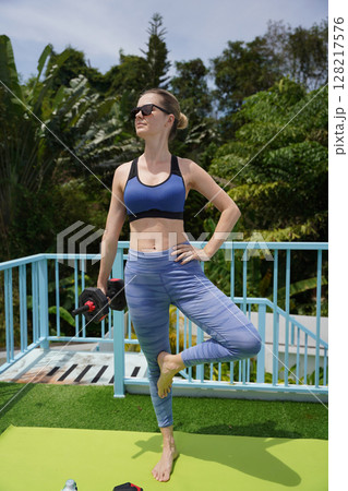 A young woman is training outdoors with dumbbells  128217576