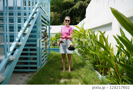 A young woman trims her beautiful garden A young woman trims her beautiful garden 128217602