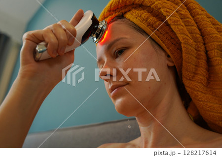 Young woman using infrared massager Young woman using infrared massager 128217614