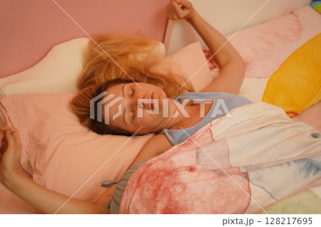 A young woman is enjoying a wonderfully serene morning in her bedroomnd A young woman is enjoying a wonderfully serene morning in her bedroomnd 128217695