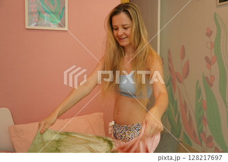 A young woman is enjoying a wonderfully serene morning in her bedroomnd  128217697