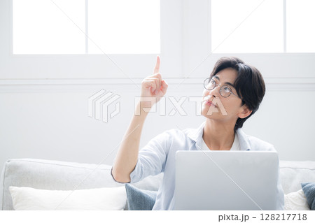 ソファに座るパソコンの前で笑顔の男性　明るい指差しポーズ 128217718