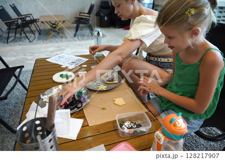 Mother and her daughter paint Halloween cookies Mother and her daughter paint Halloween cookies 128217907