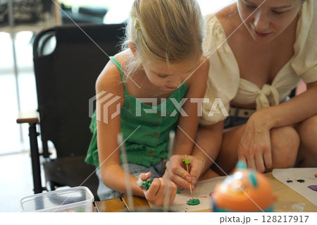 Mother and her daughter paint Halloween cookies  128217917