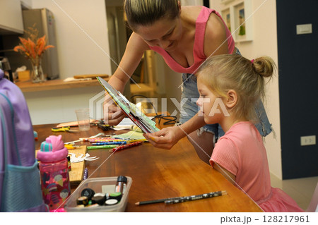 A mother and her young daughter engage in a colorful painting activity  128217961