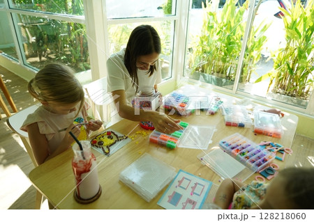 Teacher in workshop teched two girls how to assemble a thermo mosaic  128218060