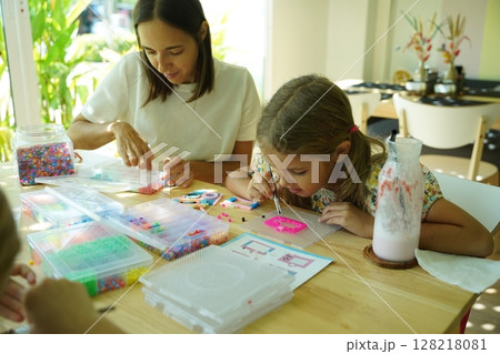 Teacher in workshop teched two girls how to assemble a thermo mosaic Teacher in workshop teched two girls how to assemble a thermo mosaic 128218081