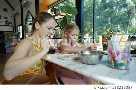 A young mother and her daughter enjoy a creative art session at home  128218087