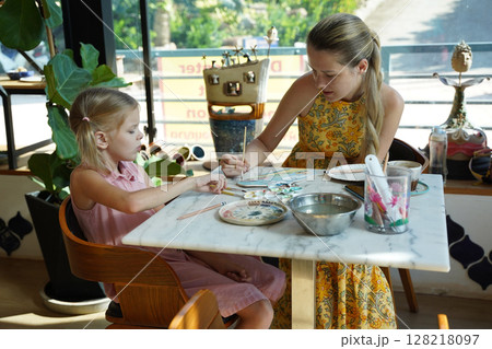 A young mother and her daughter enjoy a creative art session at home  128218097
