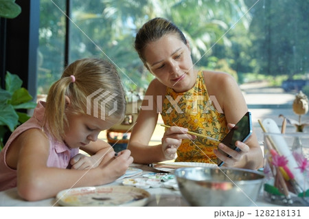 A young mother and her daughter enjoy a creative art session at home  128218131