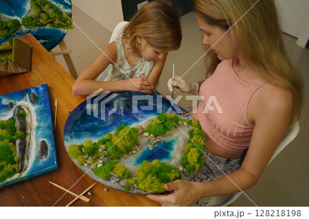 A mother and her daughter craft vibrant natural landscapes  128218198