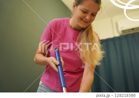 A woman is cleaning her living room at home A woman is cleaning her living room at home 128218380