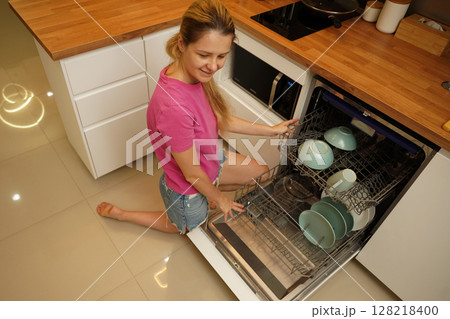 Young woman takes dishes out of the dishwasher machine 128218400