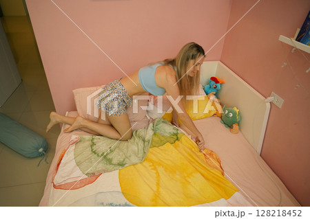 A young woman is enjoying a wonderfully serene morning in her bedroomnd A young woman is enjoying a wonderfully serene morning in her bedroomnd 128218452
