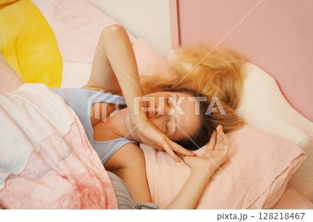 A young woman is enjoying a wonderfully serene morning in her bedroomnd A young woman is enjoying a wonderfully serene morning in her bedroomnd 128218467