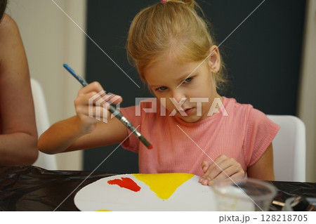 A mother and her young daughter engage in a colorful painting activity  128218705