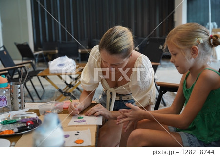 Mother and her daughter paint Halloween cookies  128218744